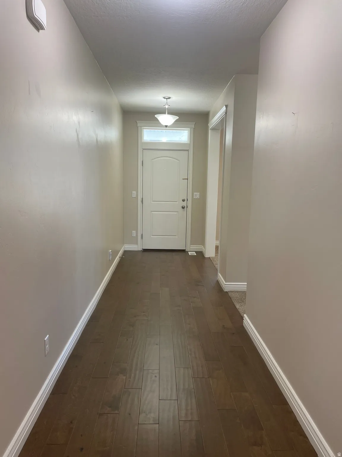 Hall featuring dark wood-style flooring and a textured ceiling