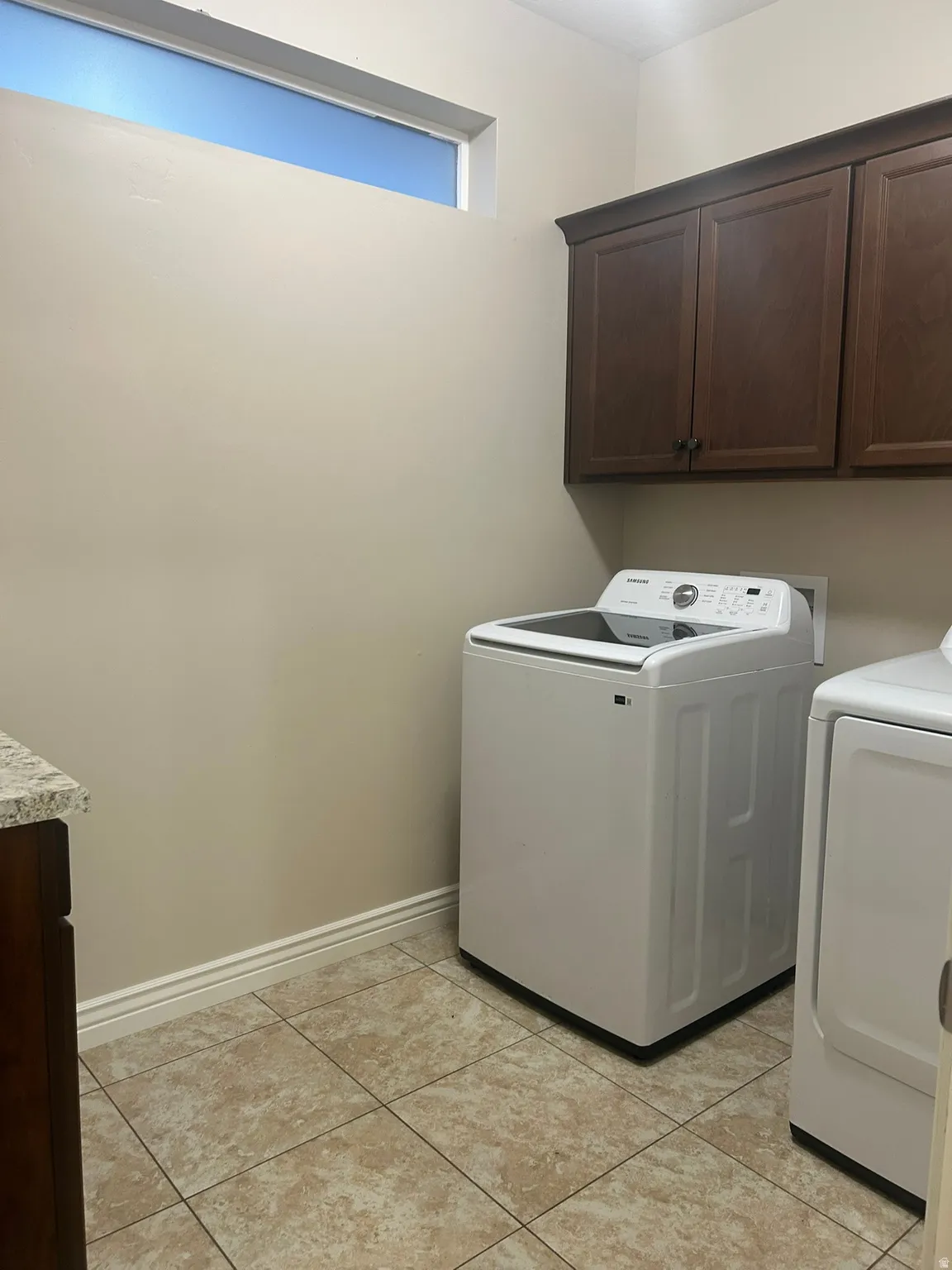 Laundry area with cabinet space, washer and clothes dryer, and light tile patterned flooring