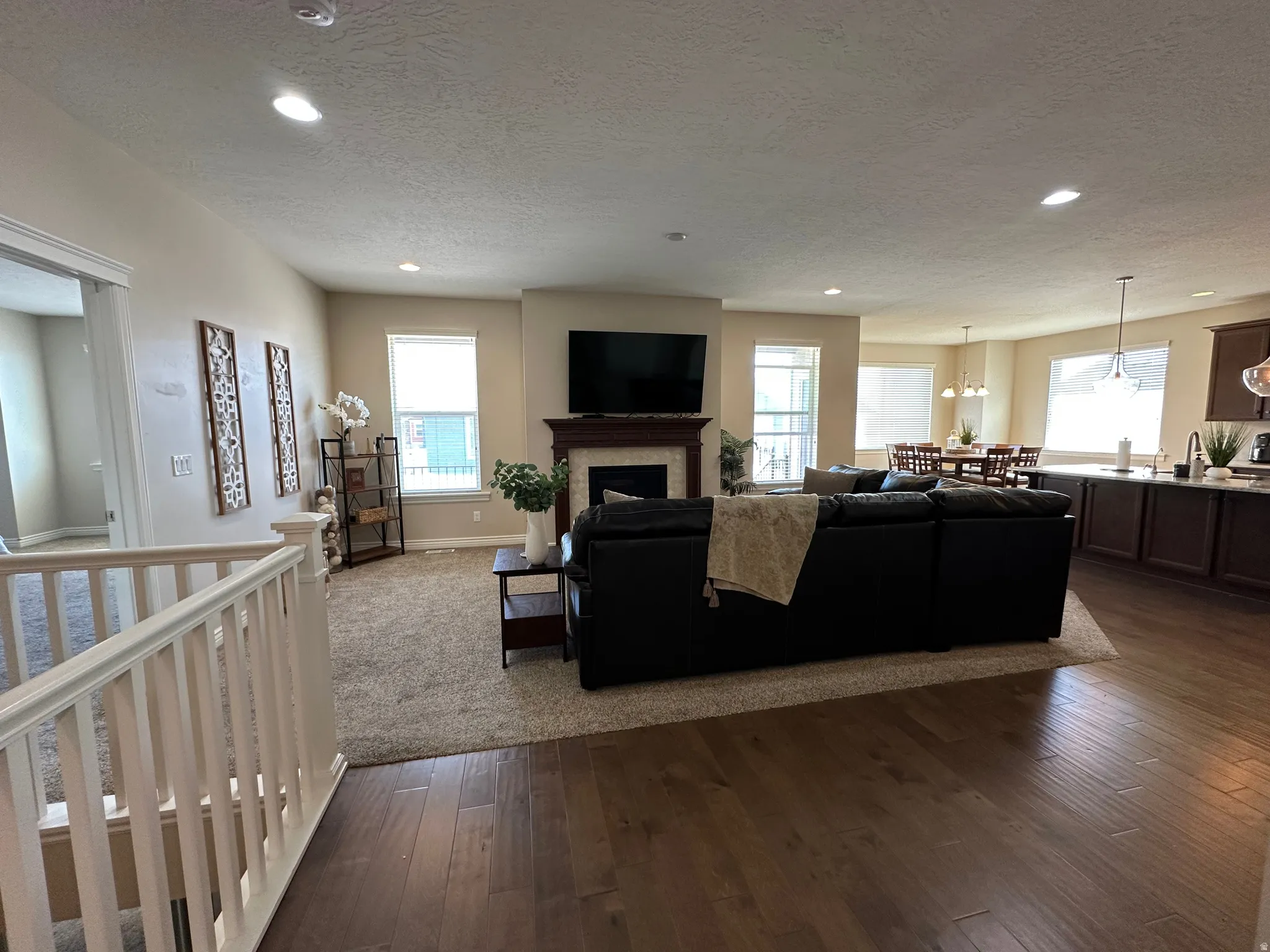 Living area with dark wood-style floors, a fireplace, recessed lighting, and a textured ceiling
