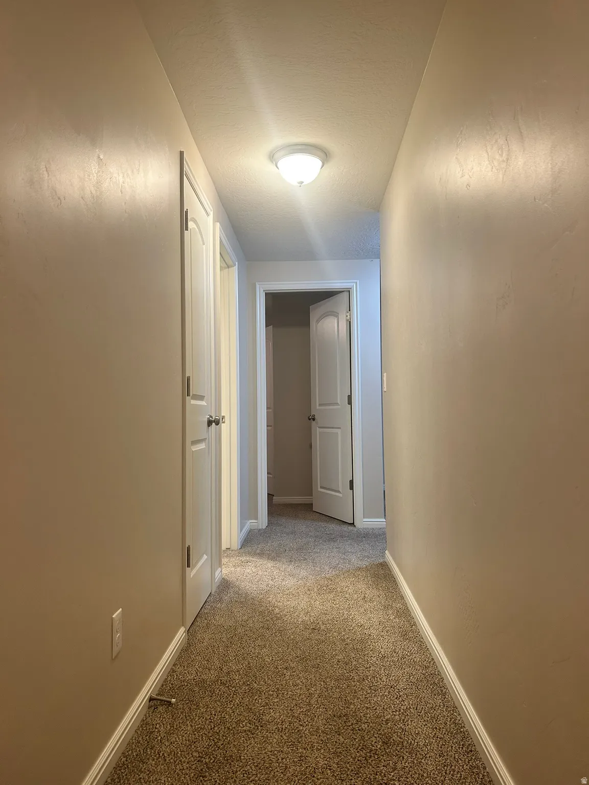 Hall featuring light colored carpet and baseboards