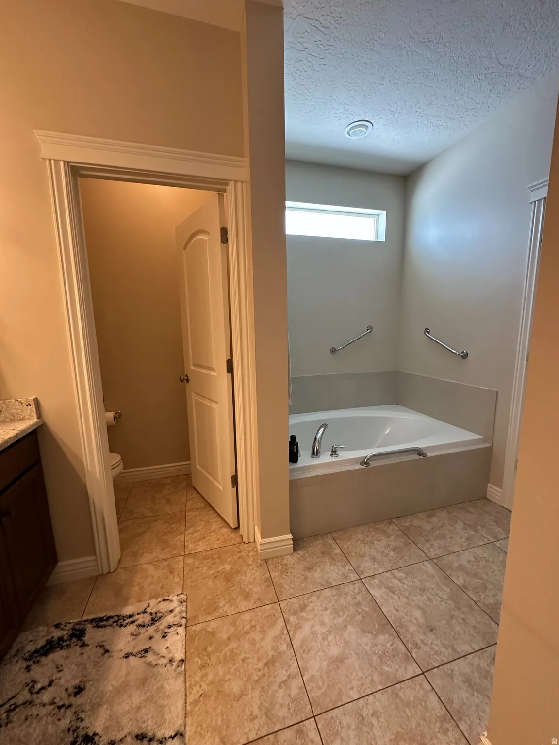 Full bathroom with a garden tub, vanity, and a textured ceiling