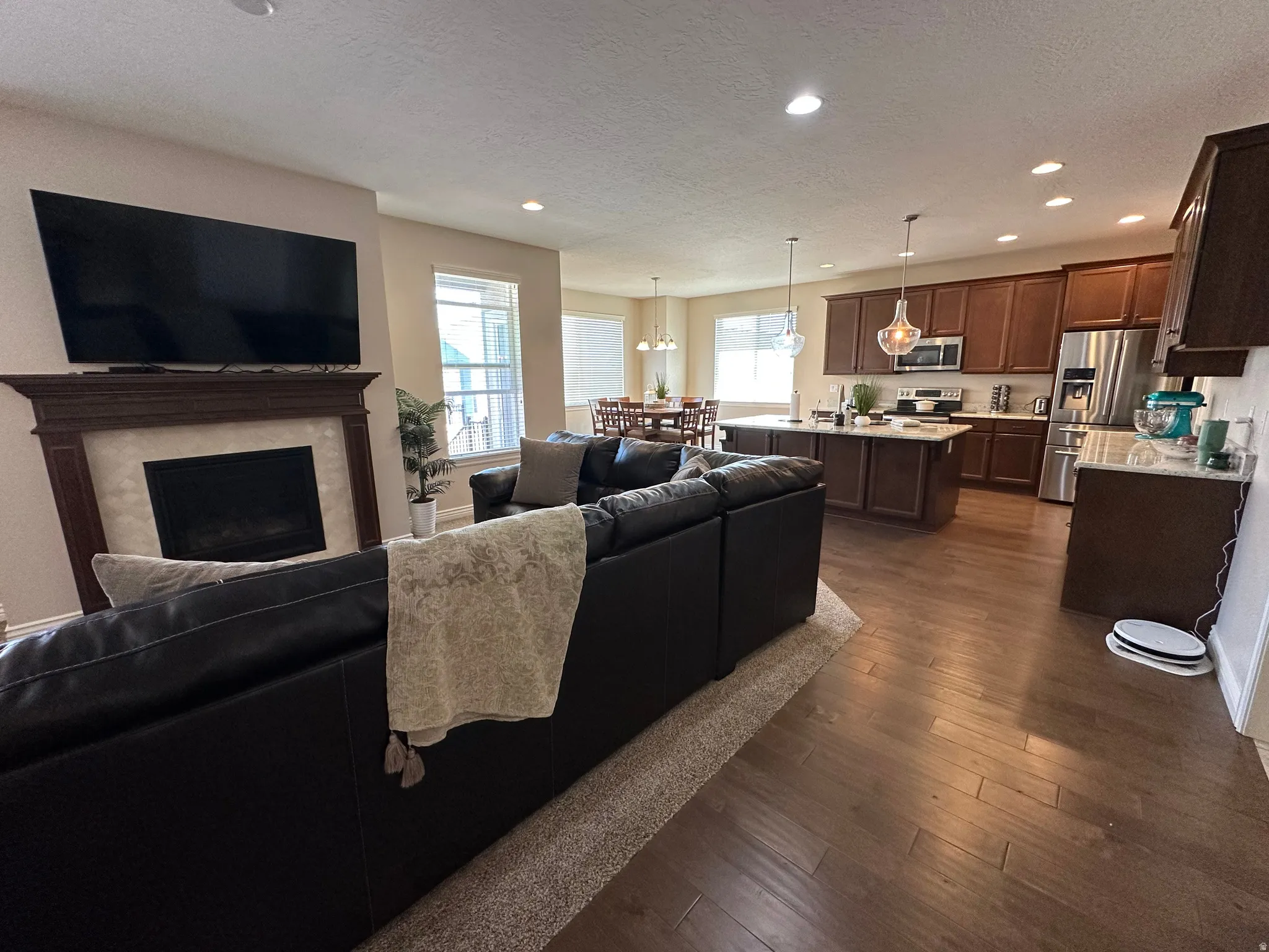 Living room featuring dark wood-style flooring, a textured ceiling, a fireplace, and recessed lighting
