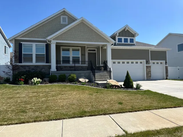 Craftsman house with stone siding, a porch, a front yard, and driveway