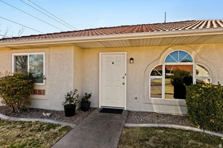 Doorway to property featuring stucco siding and a tiled roof