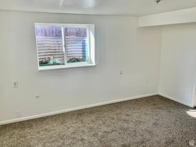 Carpeted spare room featuring baseboards