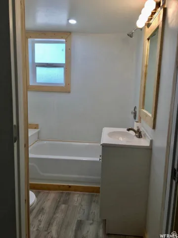 Full bath with vanity, light wood finished floors, and shower / bath combination