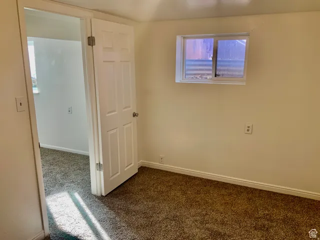 Unfurnished room featuring baseboards and dark colored carpet