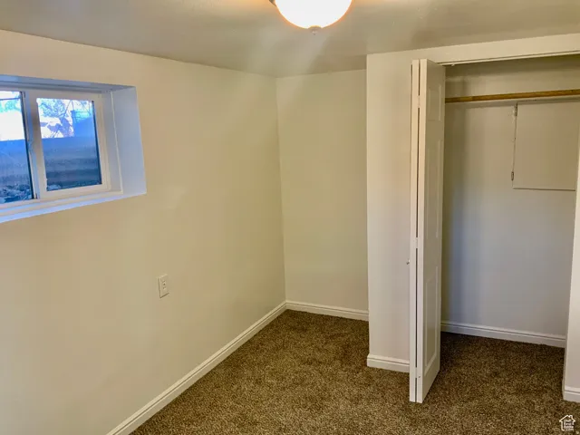 Unfurnished bedroom with dark carpet and a closet