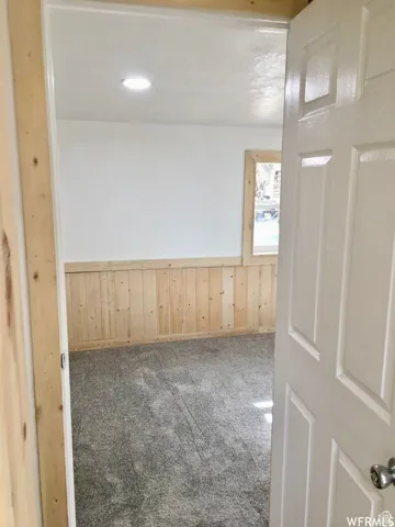 Carpeted spare room with wooden walls, a wainscoted wall, and recessed lighting