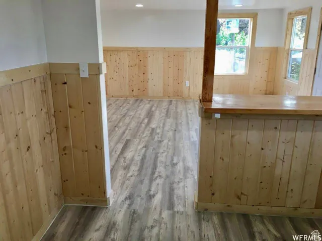 Unfurnished room featuring wainscoting, wood walls, light wood finished floors, and recessed lighting