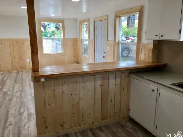 Kitchen featuring wainscoting, light wood finished floors, wood walls, white cabinetry, and butcher block countertops