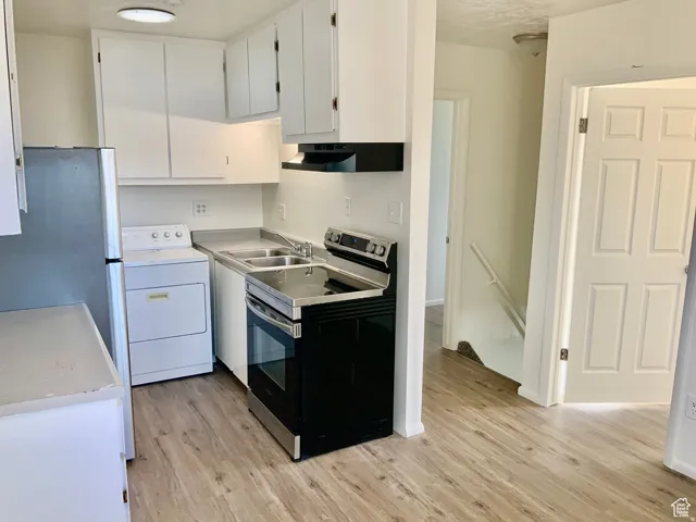 Kitchen featuring stainless steel appliances, washer / clothes dryer, white cabinets, light countertops, and light wood-style floors