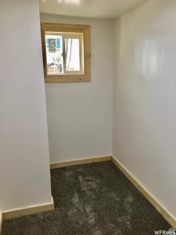 Spare room featuring baseboards and dark colored carpet