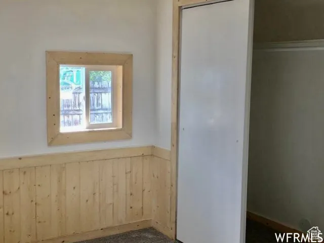 Empty room featuring wainscoting and wood walls