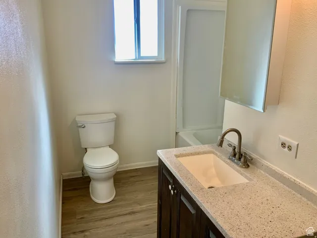 Full bath with vanity, light wood-type flooring, and a textured wall