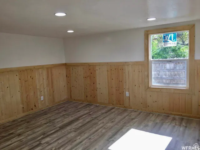 Unfurnished room with a wainscoted wall, wood walls, and wood finished floors