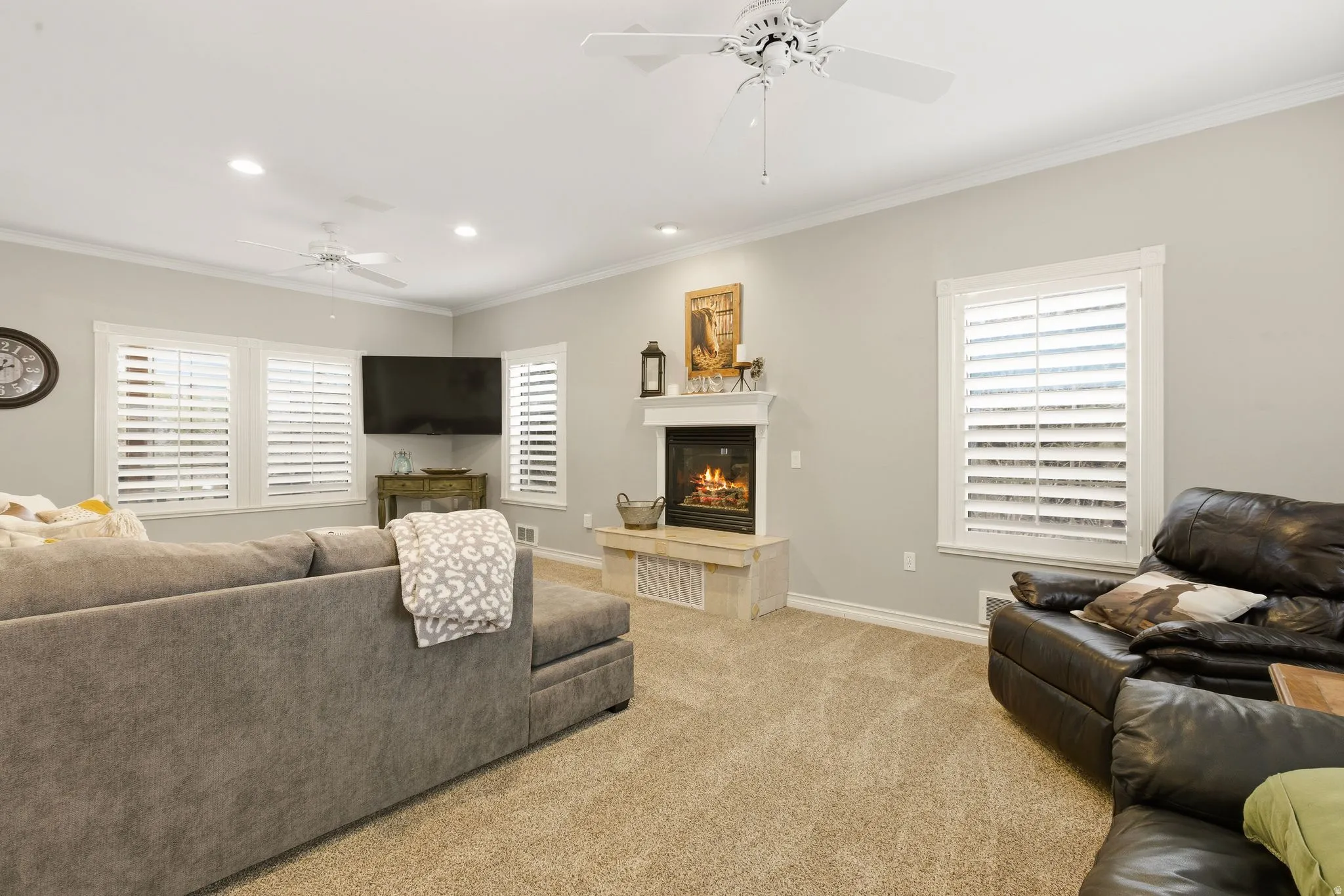 Living room featuring ceiling fan, crown molding, healthy amount of natural light, carpet floors, and a tile fireplace