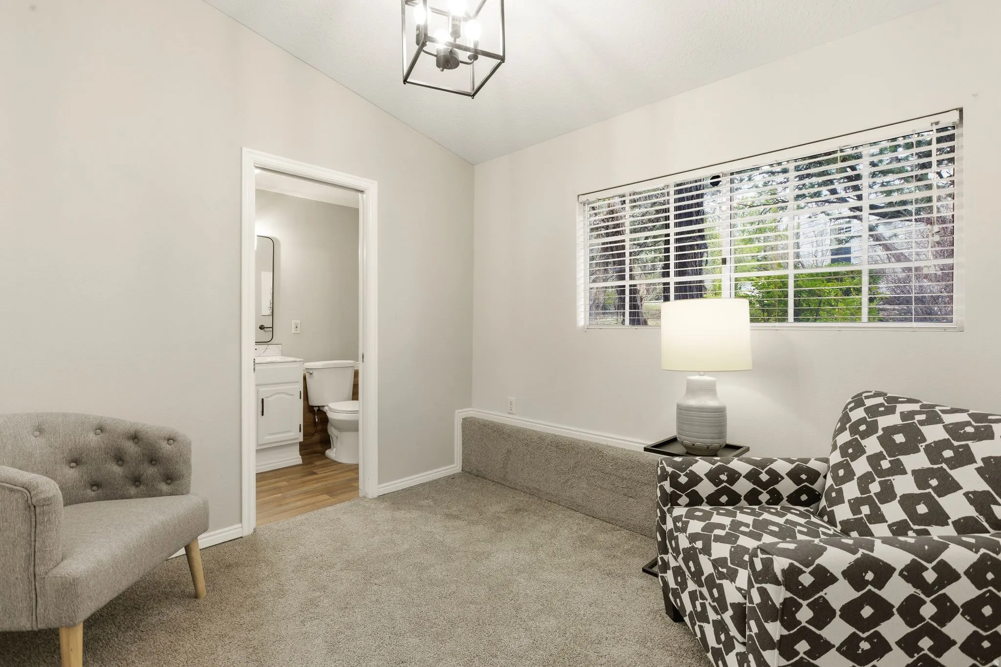 Living area with vaulted ceiling, light colored carpet, and a chandelier