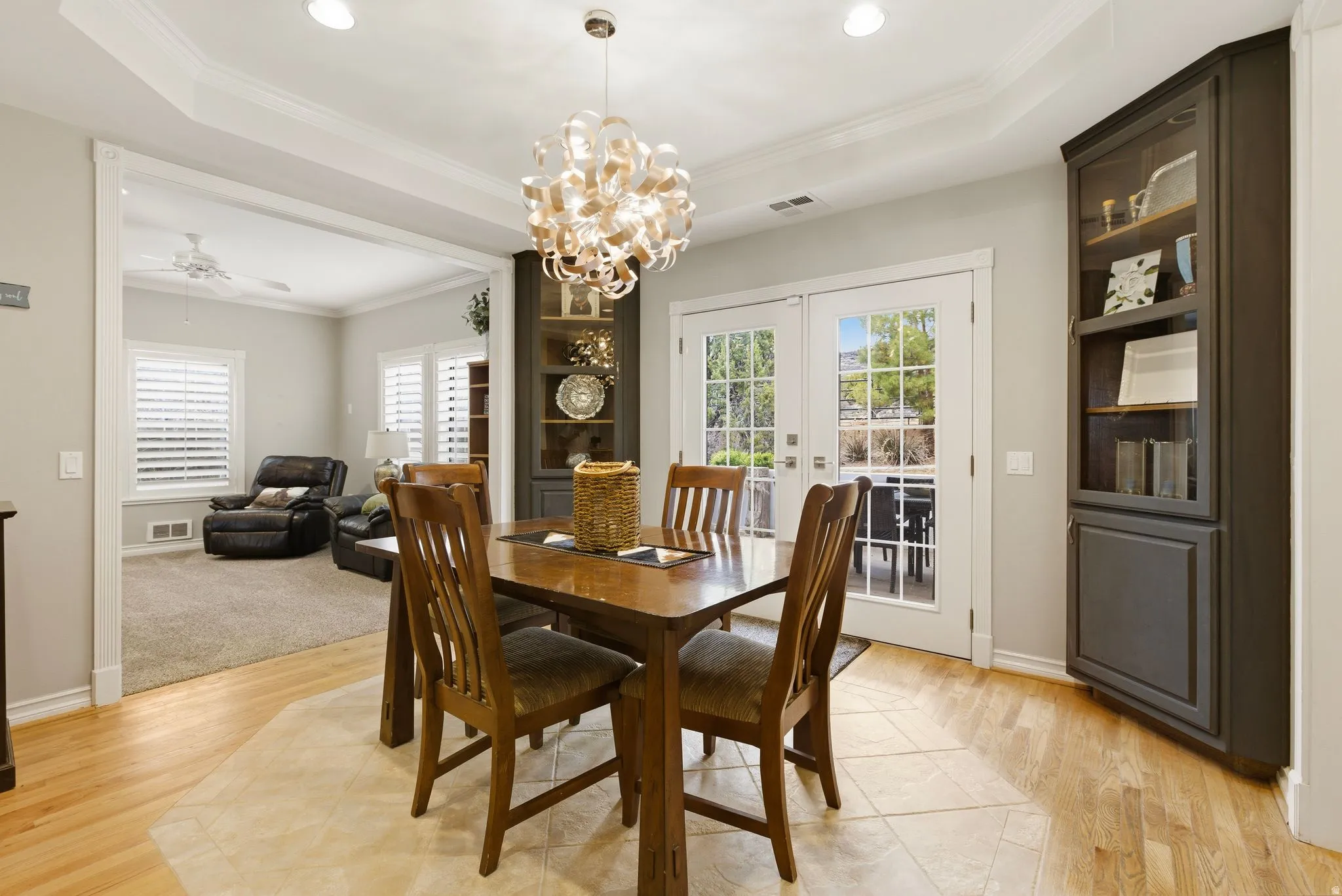 Dining space featuring crown molding, a tray ceiling, light wood finished floors, french doors, and ceiling fan