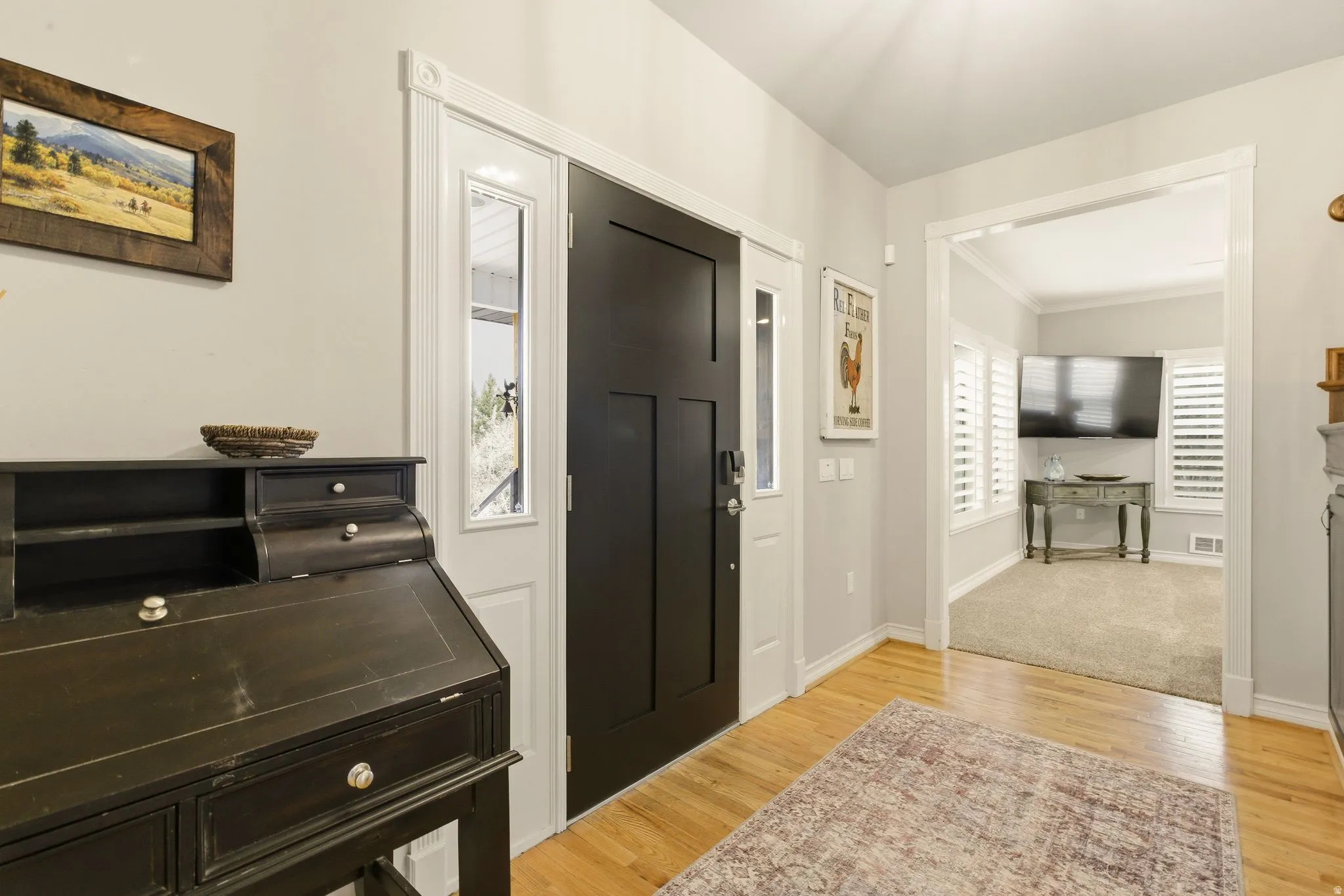 Entrance foyer with light wood-style floors, ornamental molding, and vaulted ceiling