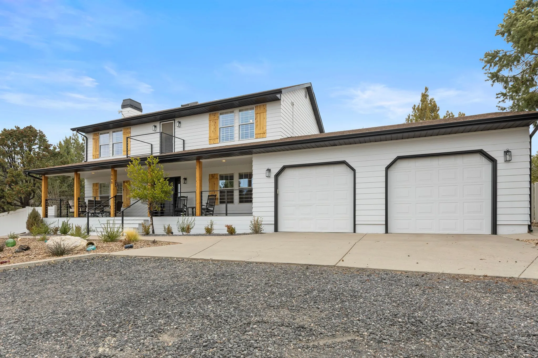 View of front of house featuring driveway, a chimney, covered porch, and an attached garage