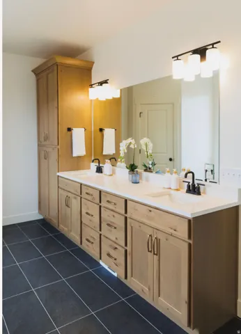 Bathroom featuring double vanity and dark tile patterned floors