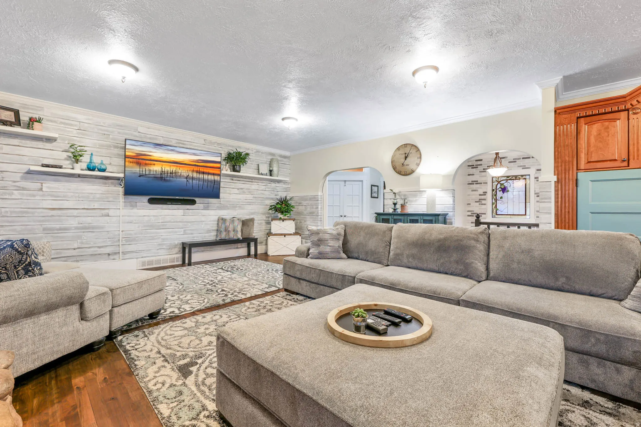 Living room with arched walkways, crown molding, a textured ceiling, and dark wood-style floors