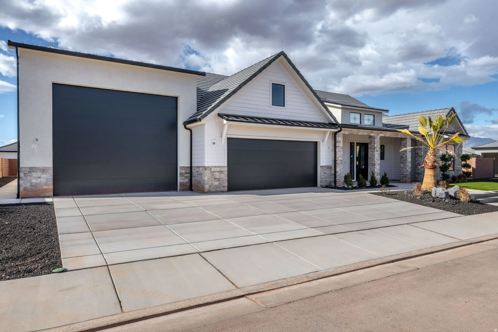 View of front of house featuring stone siding, a standing seam roof, concrete driveway, a porch, and an attached garage