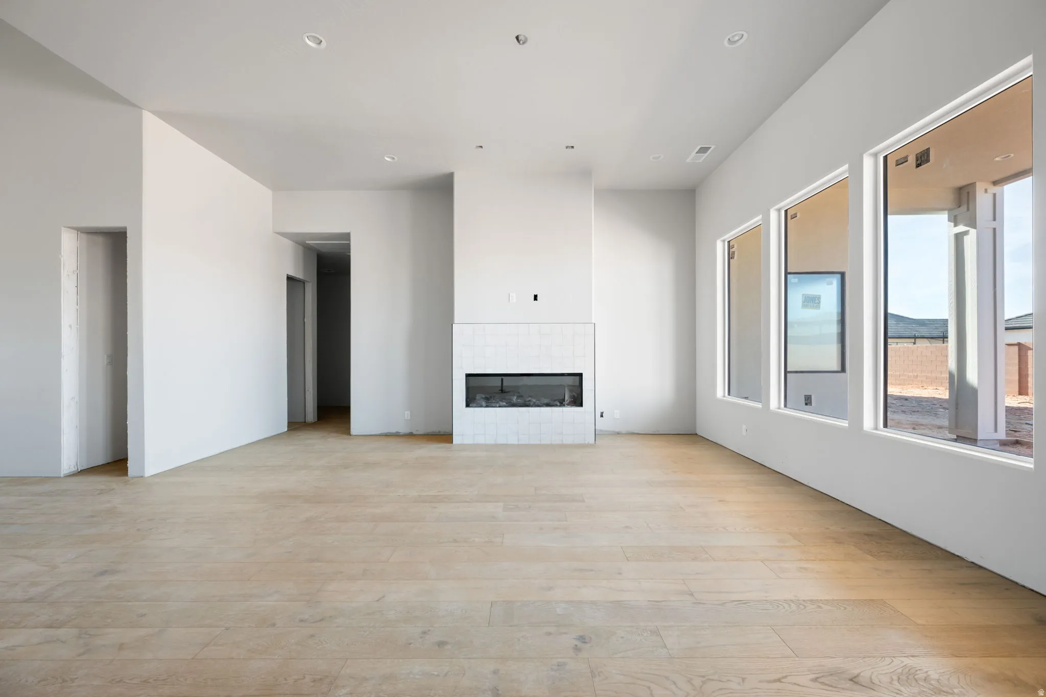 Unfurnished living room featuring light wood finished floors, a tile fireplace, and recessed lighting