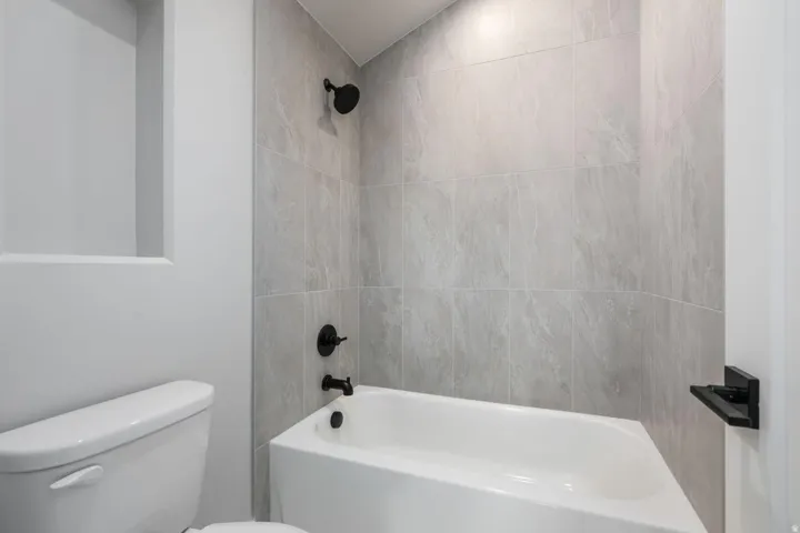 Subway tile shower surround with matte black fixtures and a built-in shower niche