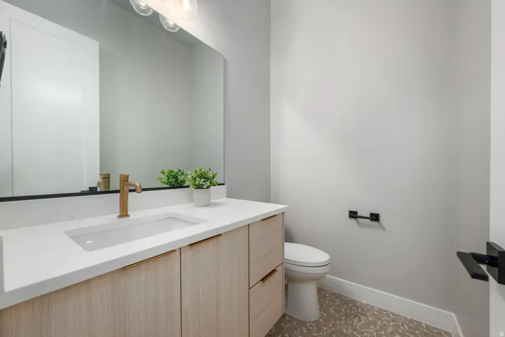 Modern vanity with a light wood-finish cabinet, gold-tone faucet, and integrated sink