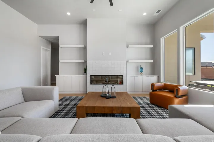 Vaulted ceilings, a built-in fireplace with tile surround, wood-finish flooring, and integrated shelving with lower cabinetry