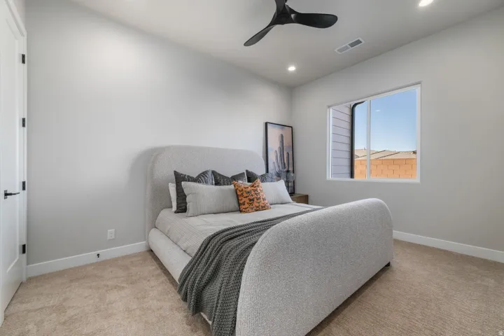 Recessed lighting, ceiling fan, white trim, light-colored carpeting, and a window providing natural illumination