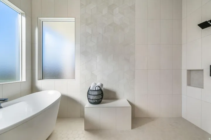 Freestanding soaking tub, large format wall tiling, geometric accent tiling, frosted window, and matte black shower fixtures