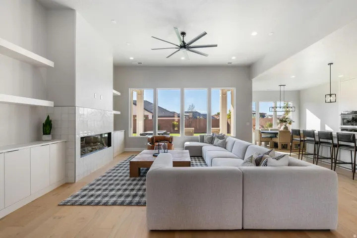 High ceilings, wood-finish flooring, built-in shelving, a linear fireplace, and multiple large windows