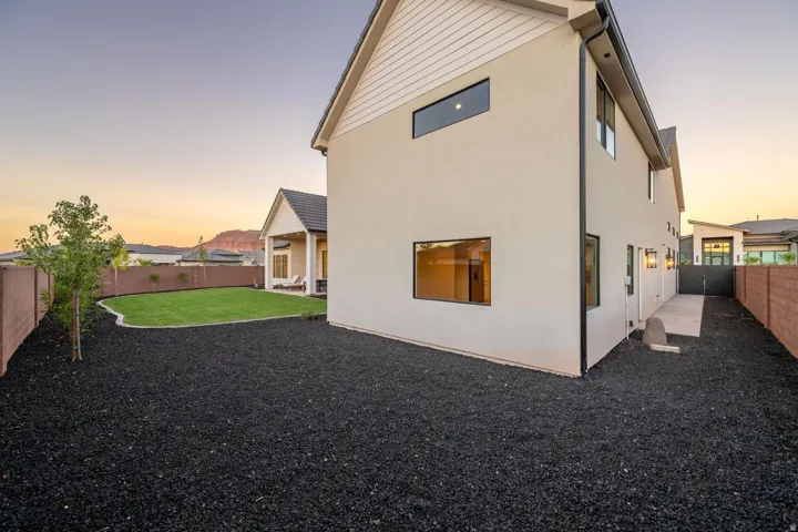 Modern stucco exterior with contrasting trim, private rear yard with a manicured lawn, and a covered patio area