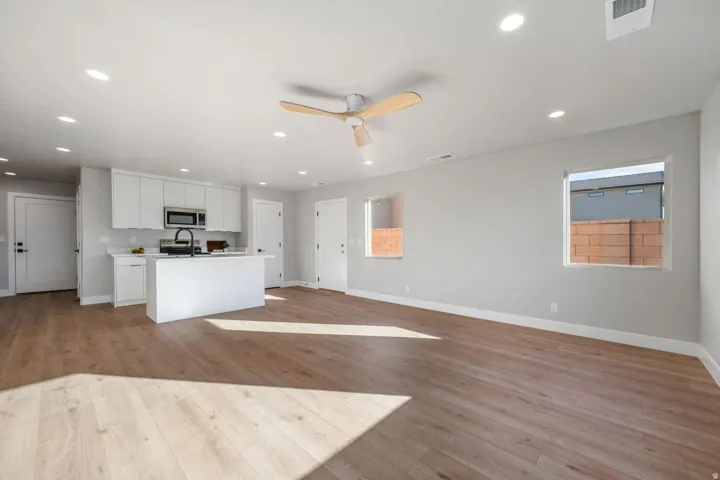 Open-concept living area with wood-finish flooring, recessed lighting, and a ceiling fan