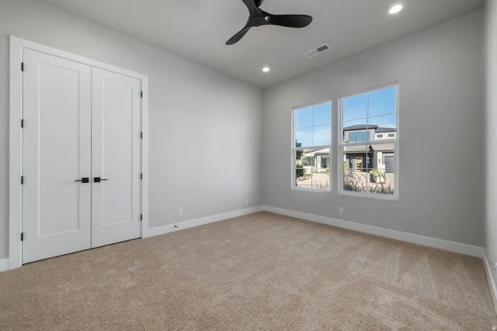 Neutral-toned carpet flooring, two large windows, a ceiling fan, and recessed lighting