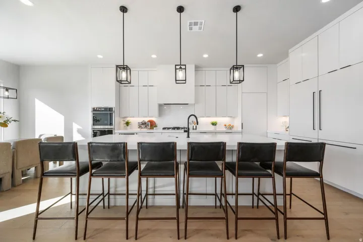 Contemporary kitchen featuring an expansive island, integrated appliances, recessed lighting, and wood-finish flooring