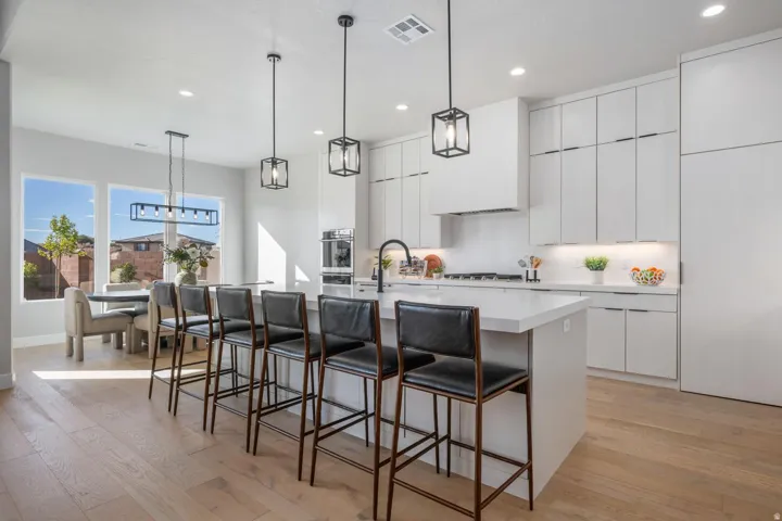 Open-concept kitchen featuring an expansive island with seating, integrated appliances, and light wood-finish flooring