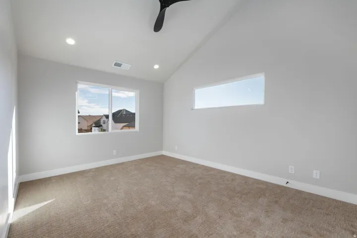 Vaulted ceiling with recessed lighting, large window, horizontal accent window, ceiling fan, and carpeted flooring