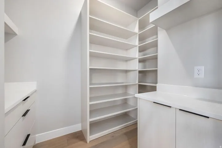 Built-in shelving, white cabinetry, integrated drawers, light wood-finish flooring, and white countertops