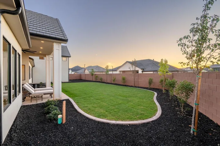 Expansive backyard with a manicured lawn, established perimeter fencing, and mature landscaping