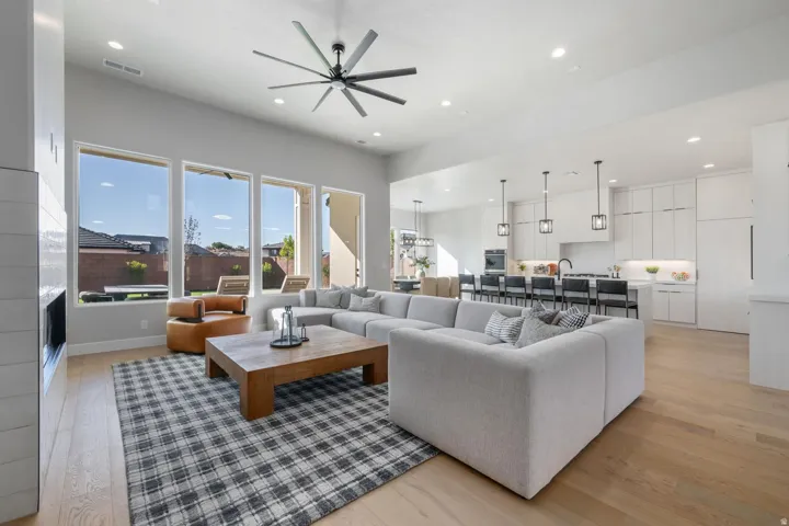 Open-concept living space featuring high ceilings, wood-finish flooring, and a modern fireplace with a tiled surround