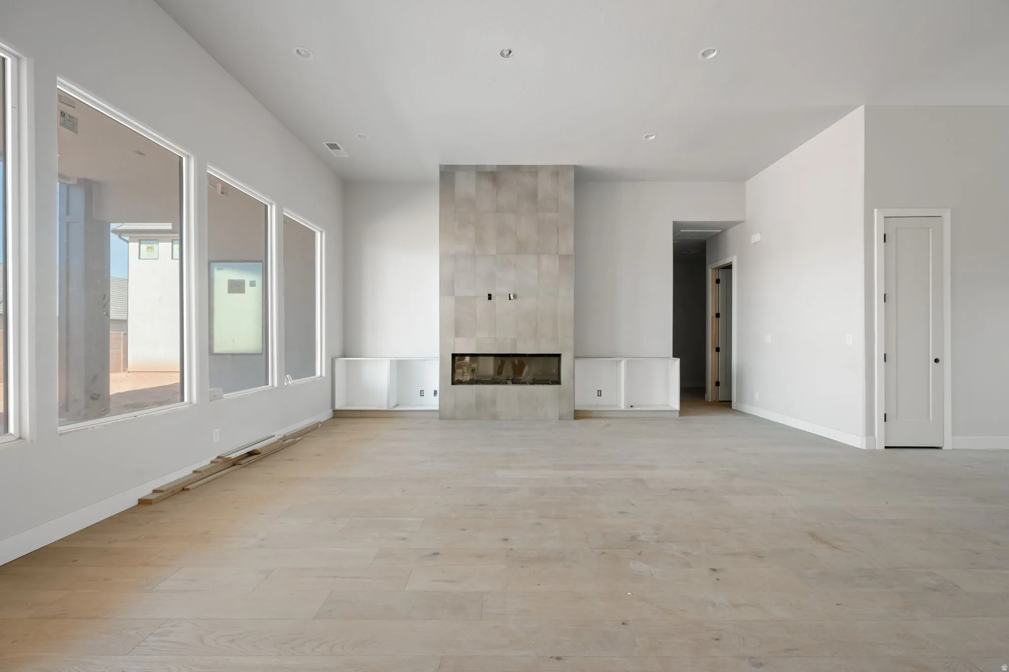 Unfurnished living room featuring a tiled fireplace and light wood-type flooring