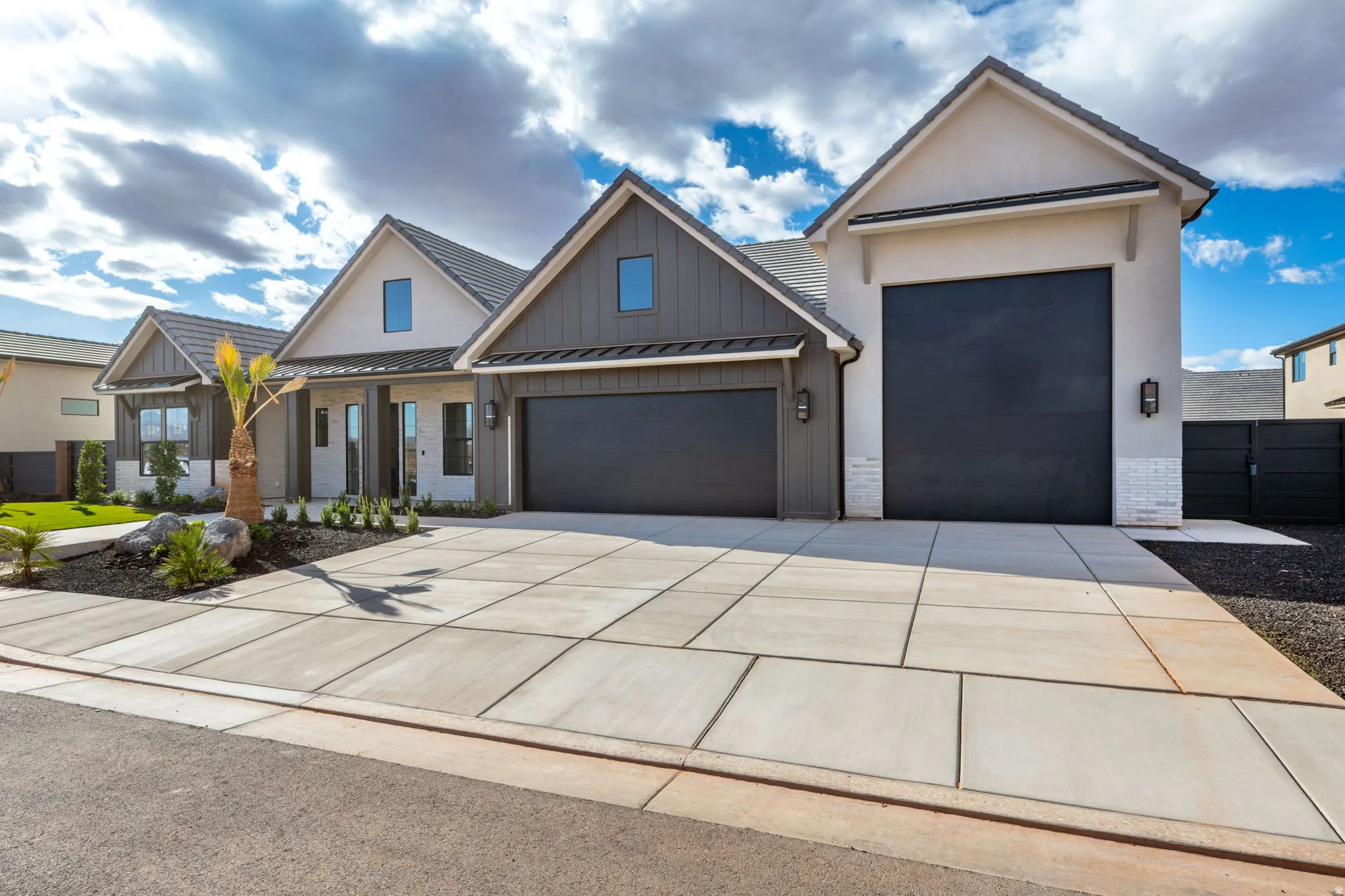 View of front facade with an attached garage, board and batten siding, a standing seam roof, and driveway