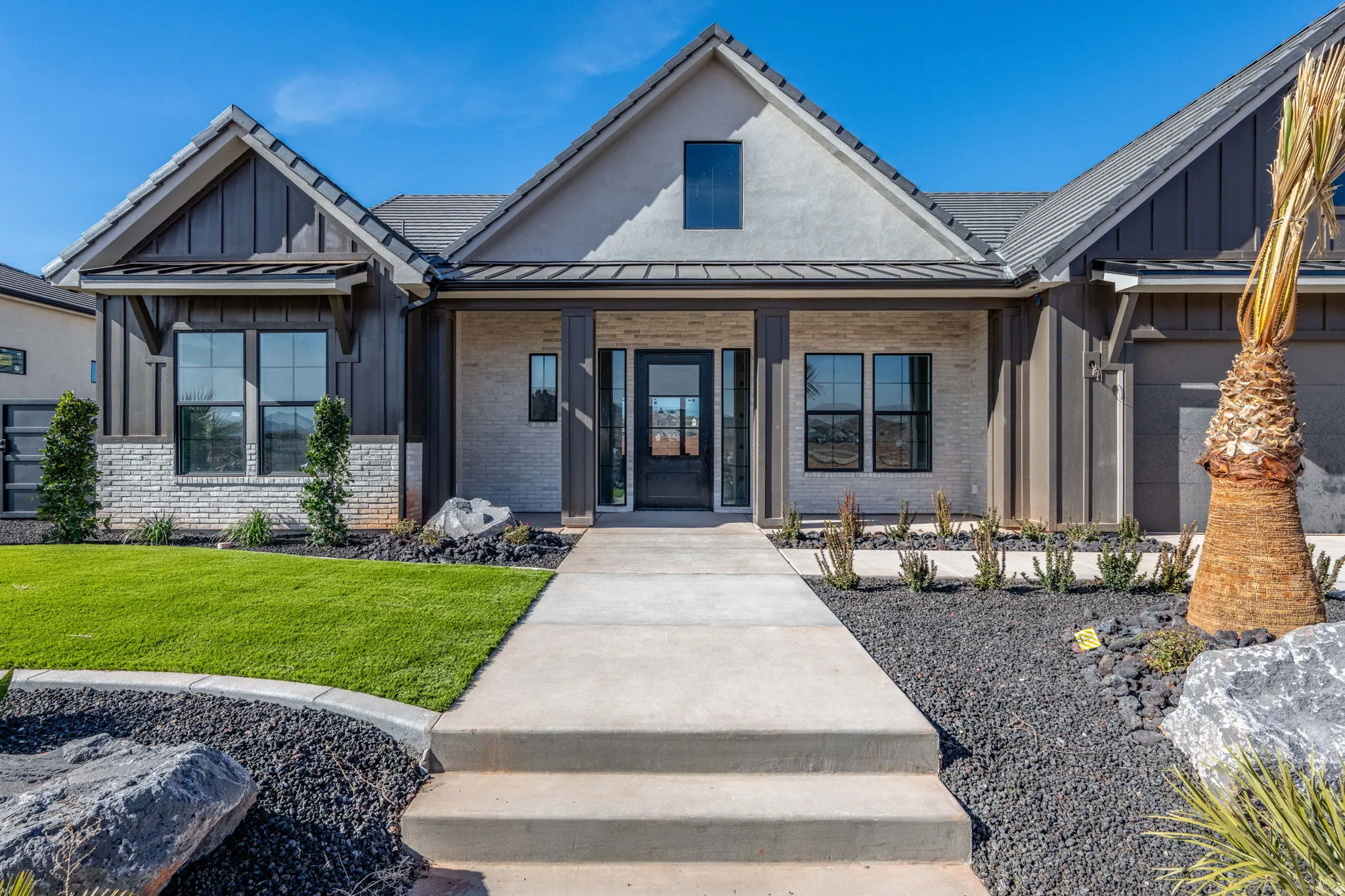 View of front of property featuring brick siding, covered porch, board and batten siding, and a front yard