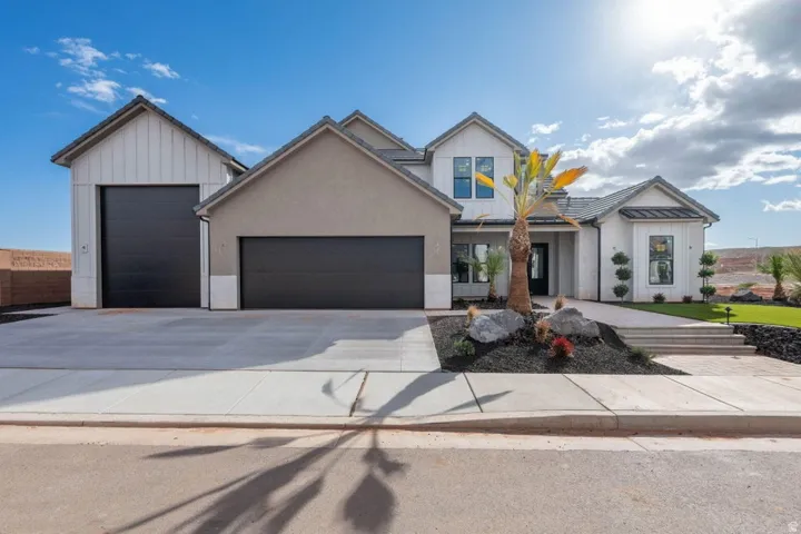 Modern inspired farmhouse featuring a standing seam roof, a garage, driveway, and board and batten siding