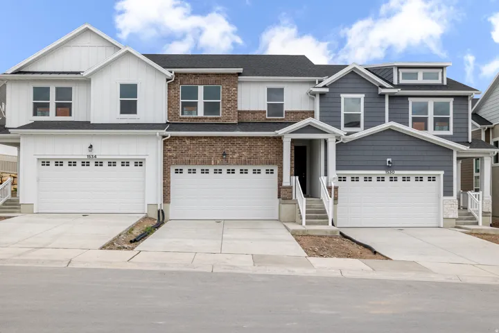 Contemporary townhome exterior featuring a mix of brick and horizontal siding, multiple two-car garages, and covered entryways with white railings