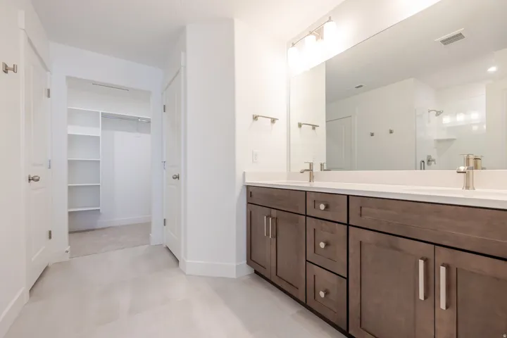 Bathroom featuring a double vanity with wood-finish cabinetry, white countertops, and brushed nickel fixtures